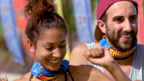 Reality TV gif. Two contestants on Survivor Australia celebrate with smiles as the woman in front holds up her fists and bounces from side to side.