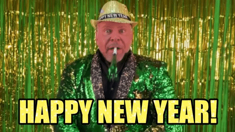 Holiday gif. In front of a bright green and gold tinsel curtain, a man dressed in an emerald green sequined suit blows into a matching colored party blower. He wears a blingy gold hat that reads, "Happy New Year," which also reads as text at the bottom.