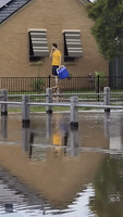 Man Walks on Stilts Through Flood Waters
