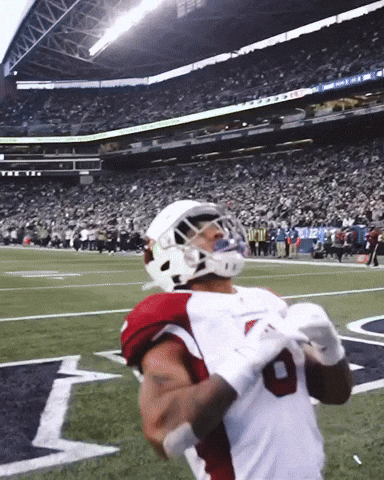 Sports gif. James Conner of the Cardinals kneels in the endzone. He pulls his hands down in front of his helmet in prayer as he shakes his head with gratitude. His teammates run up behind him and give him victorious pats on the shoulders and helmet.