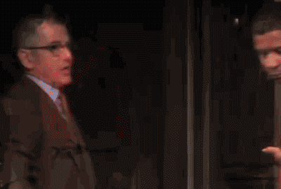 TV gif. Denzel Washington, in a theater clip from the 2014 Tony Awards, cuts off a man in a suit with glasses who is speaking to him on the other side of an open door by casually slamming the door in the man's face without looking up.