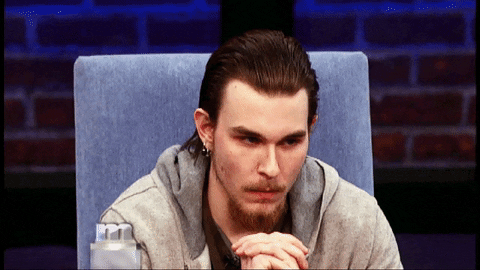 TV gif. Man on Maury leans forward nervously in his seat, with his hands folded, looking down pensively and then looking up skyward.