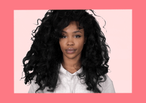 Celebrity gif. Singer Sza looks at us and places her hand on her chest. She says with almost a flirtatious gaze, “Who me?”