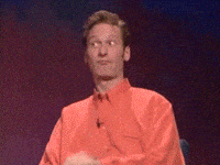 Reality TV gif. Ryan Stiles on Whose Line Is It Anyway sits on stage and makes his fingers into a circle and thrusts a finger through the circle towards Drew Carey. Drew looks back at him smiling and then makes a blowjob gesture with a thrusting fist and his tongue on his cheek.