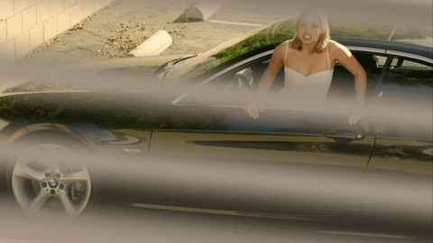 Video gif. Through window blinds, we see a woman leaning out of a car screaming, “do iiiiiiiiii!”