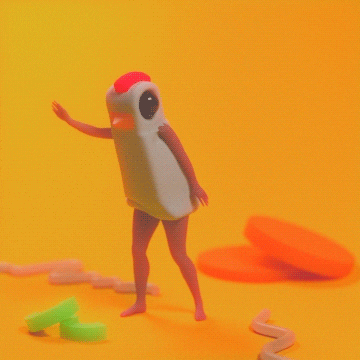 Video gif. A woman in a weird rubber chicken costume dances in a room full of giant pieces of carrots, celery and noodles.