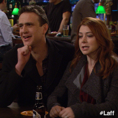 TV gif. Jason Segel as Marshall and Alyson Hannigan as Lily of How I Met Your Mother sit in a bar booth and high five above each other's heads. 