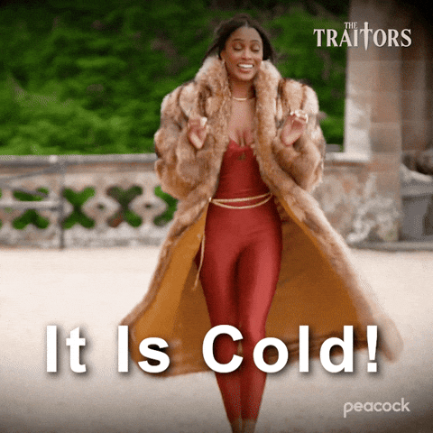 Sponsored gif. Traitors cast member Ciara Miller walks along a gravel walkway while wearing an elaborate fur coat. Text reads, “It is cold!”