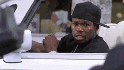 Celebrity gif. Fifty cent rests a hand on a steering wheel of a convertible and laughs as he drives off. 