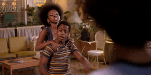 TV gif. Stefanée Martin as Yolanda in The Get Down, has her brother, Tremaine Brown Jr. as Miles "Boo-Boo", in a headlock and is giving him a noogie as he struggles. 
