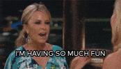 Reality TV gif. Tamra Judge on The Real HouseWives of Orange County sits across from another woman at a restaurant. Tamra leans over, shaking her hand, and says, “I'm having so much fun!”