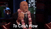 Reality TV gif. Kevin O'Leary on Shark Tank wearing a lei and holding a drink in a coconut. He toasts us and says, "To cash flow!"