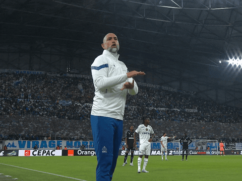Sports gif. Igor Tudor, head coach of Olympique de Marseille, stands on the field making emphatic gestures and talking intensely at someone off screen as if in disagreement. The players on the field are standing by on the field waiting for something to be decided. 