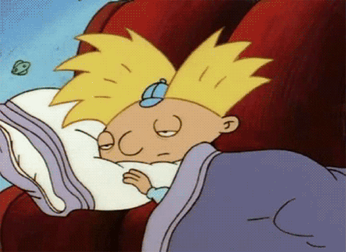 Cartoon gif. Arnold in Hey Arnold! lies on a couch with a blanket and pillow with half-lidded eyes that he struggles to keep open.