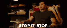 Movie gif. John Leguizamo as Mauricio in Nothing Like the Holidays sits in an armchair and waves his hand dismissively, shaking his head and saying, "stop it, stop," which appears as text.