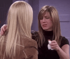 Friends gif. Jennifer Aniston as Rachel hugs Lisa Kudrow as Phoebe while holding a tissue and fighting back tears. 
