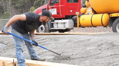 A worker is using a tamper on wet cement.