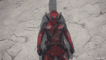 Trailer gif. A masked Ryan Reynolds as Deadpool in the trailer for the movie "Deadpool & Wolverine" is lying on his back in the desert with the shadow of Hugh Jackson as Wolverine looming over him. Reynolds looks up as the shadow of Jackman curls up his arms and unsheathes his Adamantium claws. 