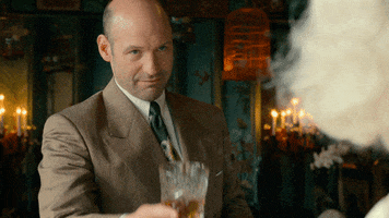 TV gif. Corey Stoll as Charles in Ratched. He's wearing a suit and he looks up as he toasts with a cocktail glass.
