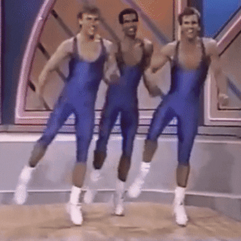 Video gif. In a retro video, three enthusiastic men wearing blue unitards and white sneakers dance in sync. Stylized 1980’s style text appears, reading “Let’s Vote Together.”