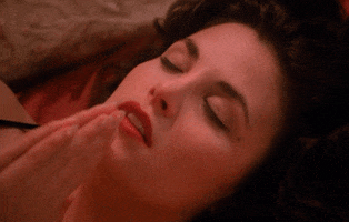 TV gif. Sherilynn Fenn as Audrey Horne on Twin Peaks lies on her back, eyes closed, praying out loud with her hands pressed together near her mouth.