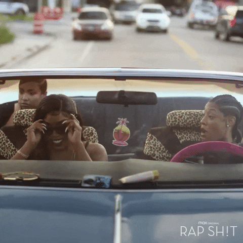 TV gif. Aida Osman as Shawna, Kamillion as Mia, and Jonica Booth as Chastity in Rap Shit cruise down the road in a convertible with the top down.
