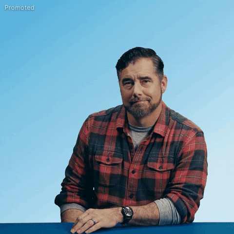 Sponsored gif. Gerald Downey wearing a plaid shirt leans in and looks at us with a warm smile as a can of Busch Light beer flies across a surface to land perfectly in his hand. He lifts the beer to give a cheers, raising an eyebrow in an inviting, playful way. Text, "Beer me."