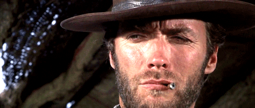 Movie gif. Wearing a cowboy hat and holding a cigarette in his lips, Clint Eastwood as the man with no name in For a Few More Dollars winks.