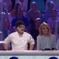 TV gif. Youtuber Cyber Marian wearing thick round glasses throws his hands up in celebration, then gives the blonde woman sitting next to him a high five.