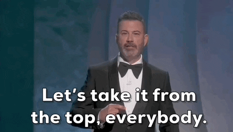 Oscars 2024 gif. Jimmy Kimmel gives a pointed hand motion to someone offstage and says, "Let's take it from the top, everybody." 
