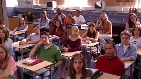 Movie gif. Rachel McAdams as Regina George in Mean Girls receives applause from her classmates. 