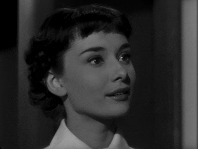 Celebrity gif. Audrey Hepburn as Princess Anne in Roman Holiday looks with gentle wonder, her smile gradually brightening with joy.