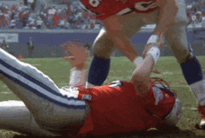 Movie gif. A football player in the Replacements shakes in terror as he lies down on a football field. Another player grasps his facemask and leans over him.