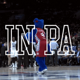 Sports gif. The mascot for the Philadelphia 76ers throws a basketball behind him without looking, making the basket as people in the crowd cheer. Text, “In PA we don’t miss an election.”