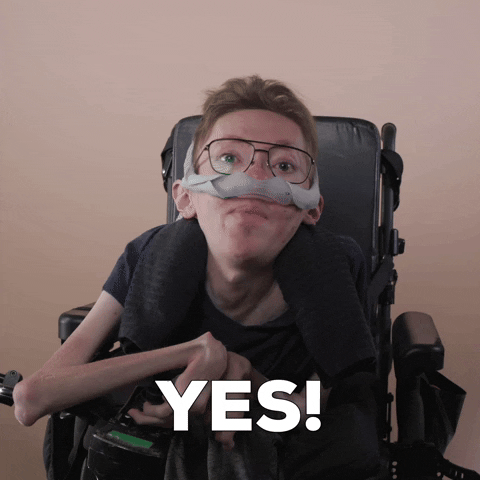 Reaction gif. A mobility-impaired white man using a power chair, a ventilator, and wearing retro-crossbar glasses decisively and excitedly says, "Yes!"