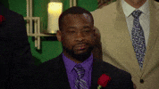 Reality TV gif. A man from The Bachelorette is standing with all the other men and he does a side eye towards the other contestants while showing a disappointed smirk on his face. 