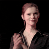 Video gif. Woman in black pajamas grins and claps slowly.