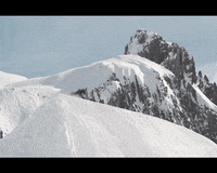 Sports gif. Snowboarder Billy Morgan spins as he flies over the ledge of hill, then crash lands and slides down the snowy slope.