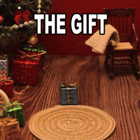 Sponsored gif. A hand places a gingerbread man into a holiday scene. The cookie is wearing a Canada Dry sweater and is lounging in a relaxed position. Text: "THE GIFT IS ME"