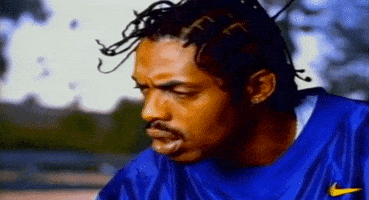 Music video gif. Coolio in 1,2,3,4 (Sumpin' New) turns to look at us with a confused or questioning frown.