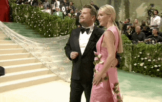 Met Gala 2024 gif. James Corden poses with his wife Julia Carey, mugging broadly to the left and then the right and back again.