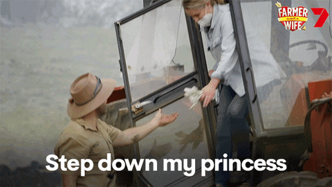 Reality TV gif. On Farmer Wants a Wife a man offers his hand to a woman as she hops down from a tractor. Text, "Step down my princess."