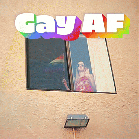 Video gif. A woman is seen in her window coolly waving a LGBTQIA flag. We zoom in in on her and she never breaks expression or stops waving the flag. Text, "Gay AF."
