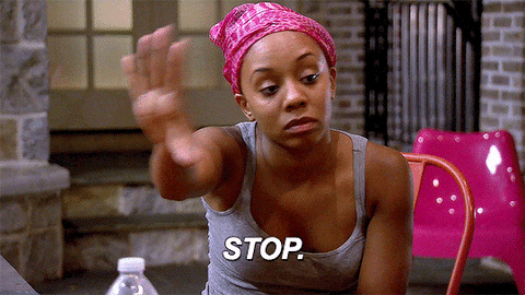 TV gif. A woman in a pink bandana holds up a hand while looking in the other direction. Text, "Stop."
