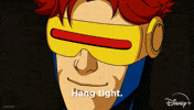 TV gif. A scene from the animated TV show "X-Men 97" shows a suited-up Cyclops smirking confidently as he taps his visor with his forefinger and says "Hang tight." He then shoots a red laser beam of energy from his visor. 