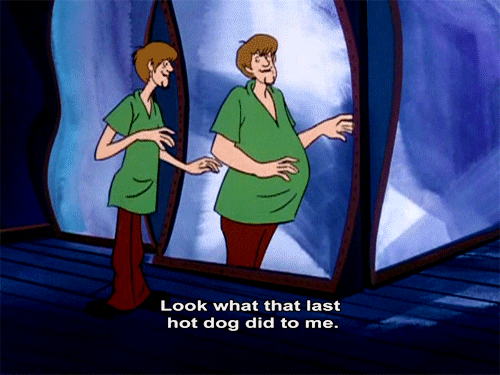 Cartoon gif. Shaggy from Scooby Doo looks at himself in a distorting funhouse mirror. His scraggly body appears thick and heavy set in the mirror. 