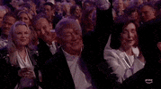 TV gif. An older gentleman in the audience at the 2024 ACM Awards happily raises his hand, then pumps his fist, happy to be recognized.