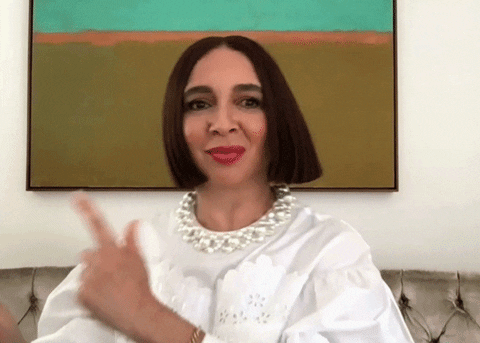 Celebrity gif. Maya Rudolph does a little dance as she sits. She points with her fingers and shimmies her shoulders to each side. Her blunt bob haircut shimmies with her. She then ends her little dance with her hands spreading out in a rainbow motion.