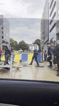 Workers in Office Attire Get Help Crossing Flooded Road Near EU Commission HQ