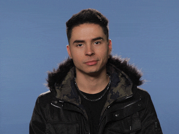 Celebrity gif. Reykon, a Colombian reggaeton artist, raises an eyebrow at us and shrugs his shoulders, leaning to the left. 